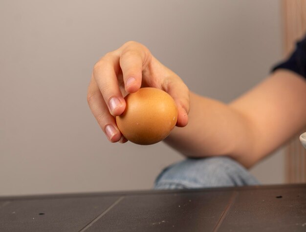 Foto mão de criança com um ovo cozido que está prestes a quebrar na mesa