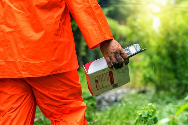 Mão de empregada segurando o velho móvel com caixa postal sobre a floresta