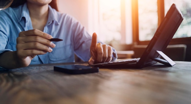 Mão de empresária trabalhando com tablet de computador portátil e telefone inteligente no escritório moderno com diagrama de ícone virtual no escritório moderno na luz da manhã