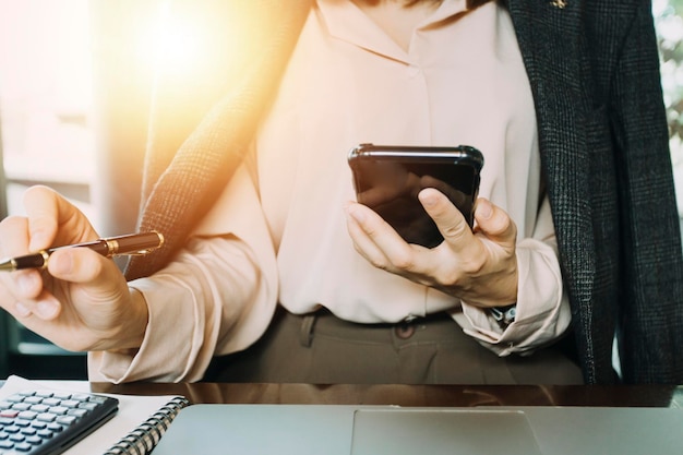 Mão de empresária trabalhando com tablet de computador portátil e telefone inteligente no escritório moderno com diagrama de ícone virtual no escritório moderno na luz da manhã