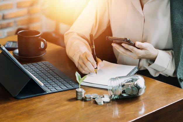 Mão de empresária trabalhando com tablet de computador portátil e telefone inteligente no escritório moderno com diagrama de ícone virtual no escritório moderno na luz da manhã