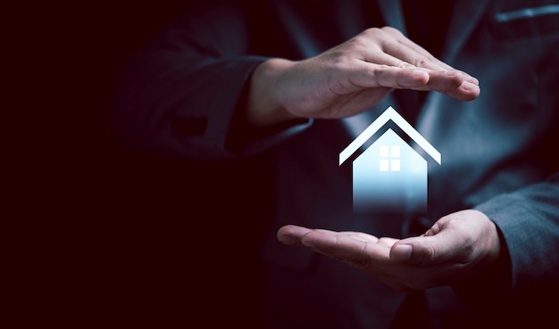Mão de empresário protegendo a casa virtual para o conceito de seguro de propriedade imobiliária.