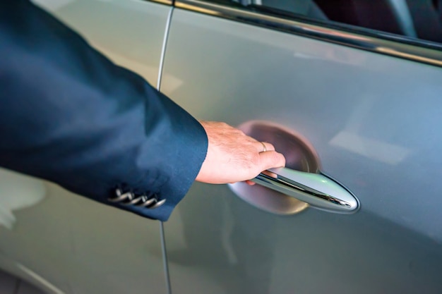 Mão de empresário segurando a alça de carro