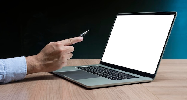 Mão de empresário segurando caneta para exibir laptop e calculadora na mesa