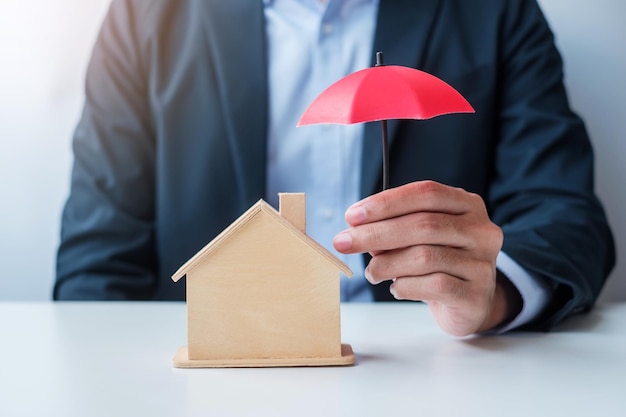 Mão de empresário segurando uma capa de guarda-chuva vermelha de madeira modelo doméstico seguro imobiliário e conceitos de propriedade