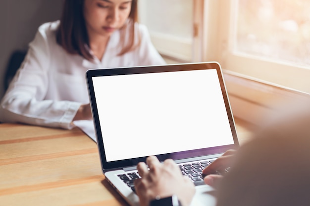 Mão de empresário trabalhando laptop tela em branco na mesa de madeira no escritório