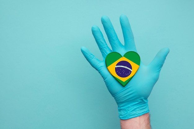 Foto mão de enfermeira de coração de saúde médica do brasil segurando a bandeira do coração do país