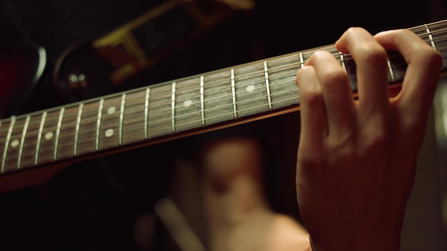 Mão de guitarrista tocando violão no estúdio Homem irreconhecível ensaiando no interior