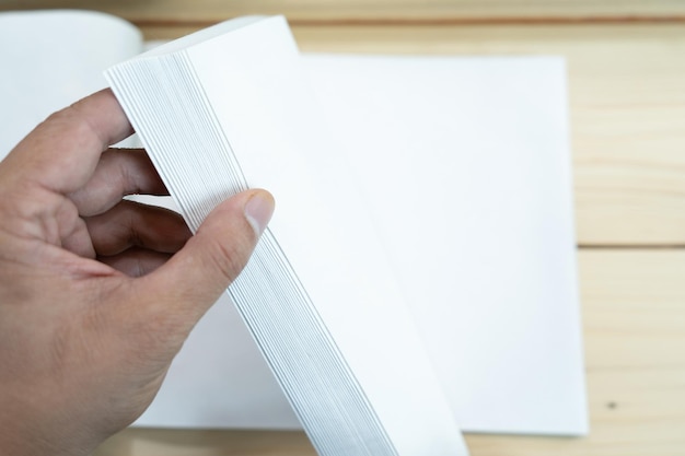 Mão de homem abre o caderno branco vazio na mesa de madeira