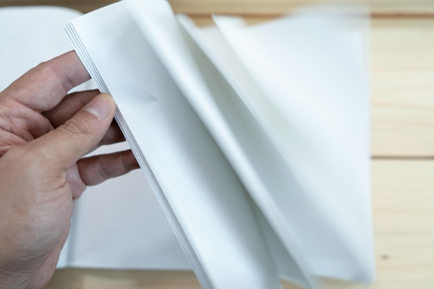 Mão de homem abre o caderno branco vazio na mesa de madeira