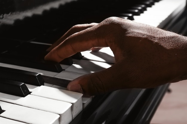 Mão de homem afro-americano tocando piano