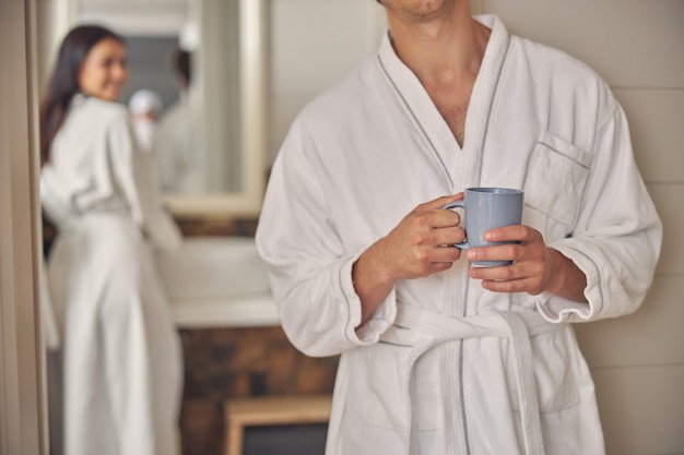 mão de homem bonito segurando uma xícara de chá no banheiro