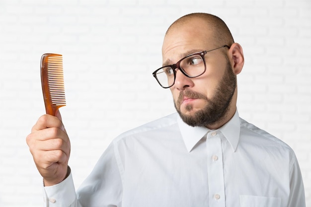 Mão de homem careca adulto segurando o pente