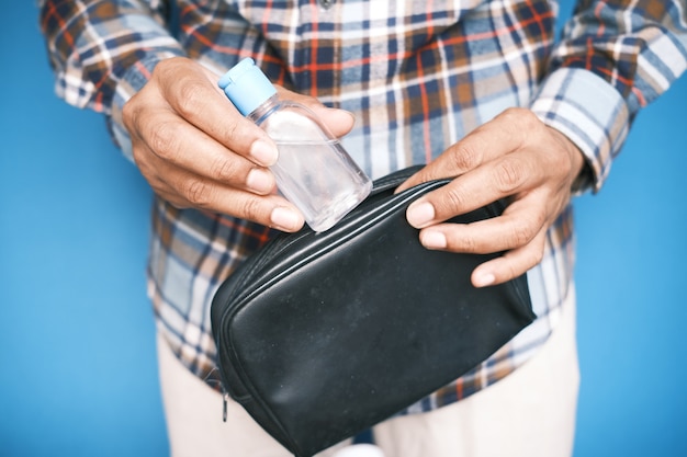 Mão de homem colocando desinfetante para as mãos em uma pequena bolsa