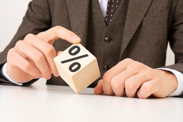 Mão de homem de negócios colocando bloco de cubo de madeira com conceito de negócio de ícone de símbolo de porcentagem