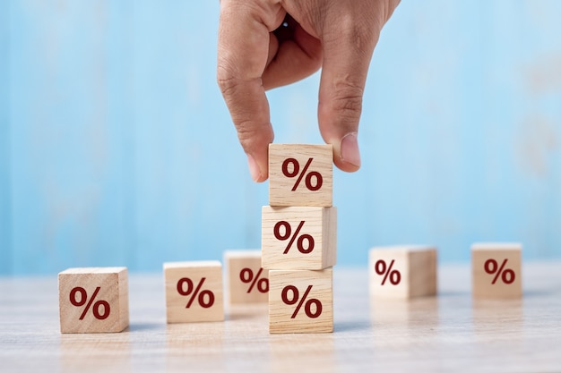 Mão de homem de negócios colocando bloco de madeira do cubo com o ícone do símbolo de porcentagem.