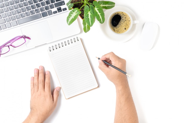 Mão de homem de negócios escrevendo em um caderno em branco com laptop e café isolado no fundo branco, vista superior e espaço de cópia