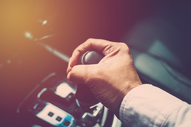 mão de homem de negócios mudando de marcha durante a condução do carro.