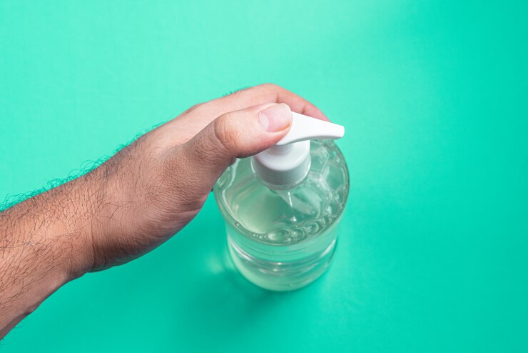 Foto mão de homem em recipiente com gel de álcool na parede azul clara