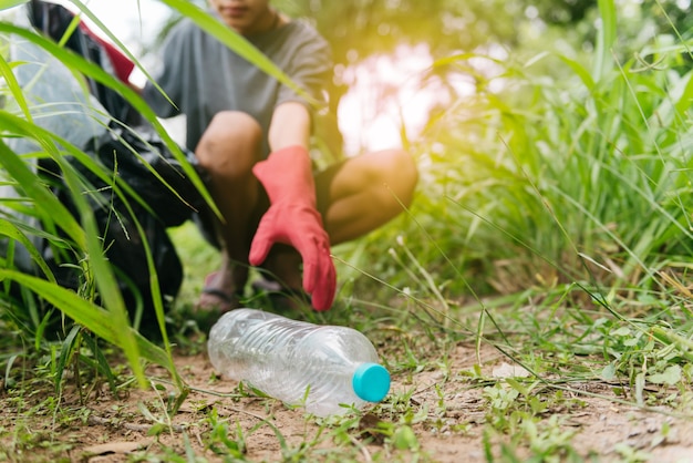 Mão de homem menino pegar uma garrafa de plástico na floresta. conservação da natureza e conceito de meio ambiente.