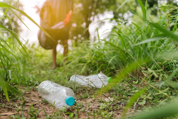 Mão de homem menino pegar uma garrafa de plástico na floresta. conservação da natureza e conceito de meio ambiente.