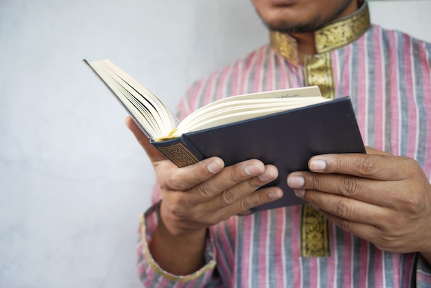 Mão de homem muçulmano lendo o livro sagrado do Alcorão com espaço de cópia