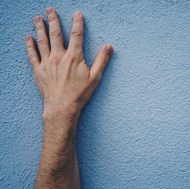 mão de homem na parede azul na rua