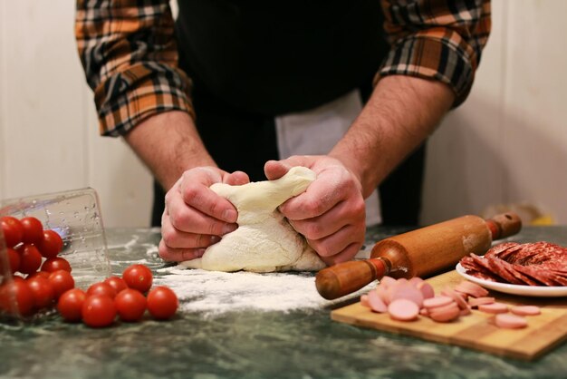 Mão de homem preparar cobertura de massa de pizza