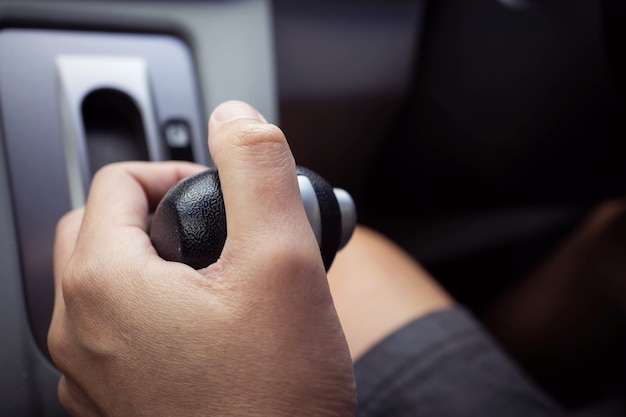 Mão de homem segurando a alavanca de câmbio em um carro