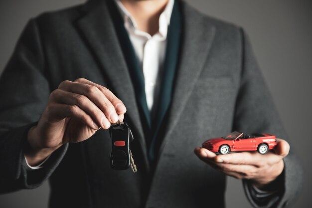 Mão de homem segurando a chave com o modelo do carro