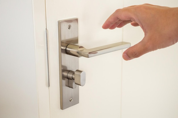 Mão de homem segurando a maçaneta da porta de perto