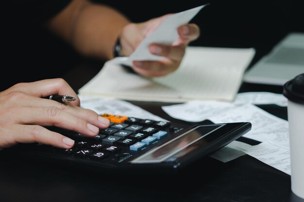 Mão de homem segurando caneta e calculadora de despesas ou conceito de finanças de negócios de recibo de imposto