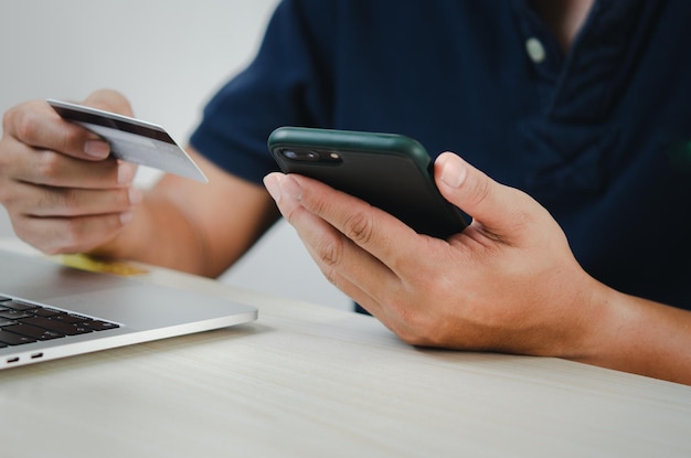 Mão de homem segurando cartão de crédito e telefone celular compras on-line ecommerce e internet banking