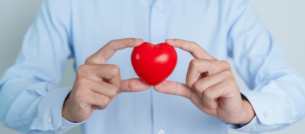 Mão de homem segurando forma de coração vermelho amor doador dia mundial do coração dia mundial da saúde e conceitos de seguro