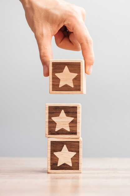 Foto mão de homem segurando o bloco estrela. o cliente escolhe a classificação para comentários do usuário. avaliação do serviço, classificação, revisão do cliente, satisfação, avaliação e conceito de feedback