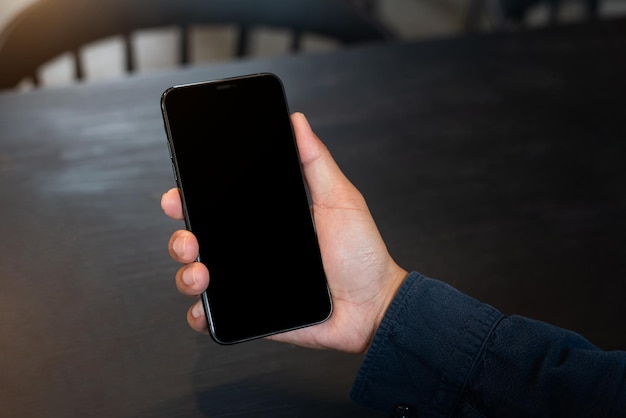 Mão de homem segurando o dispositivo de smartphone no café