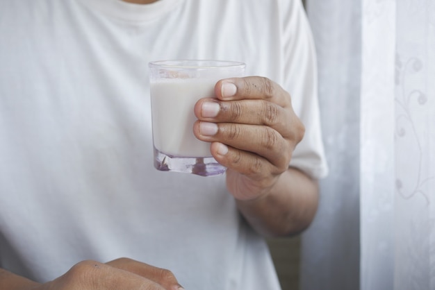 Mão de homem segurando um copo de leite no início da manhã