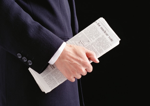 Mão de homem segurando um jornal