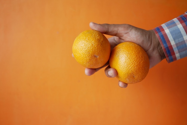 Foto mão de homem segurando uma fatia de fruta laranja i contra um fundo laranja