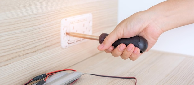 Mão de homem usando chave de fenda instalando cabos de fio para tomada de tomada renovação reparação de fixação e desenvolvimento de conceitos de casa e apartamento