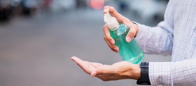 Mão de homem usando dispensador de gel de desinfetante para as mãos, contra novos coronavírus ou doença de vírus de corona (covid-19) em público ao ar livre.