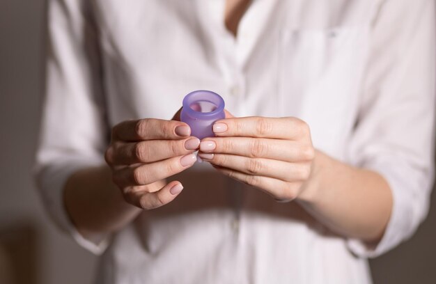 Foto mão de jovem segurando o copo menstrual foco seletivo e dof raso