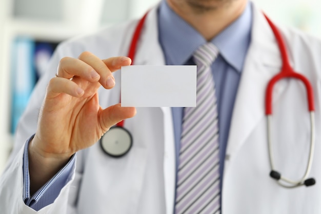 Mão de médico de medicina masculina segurando o cartão em branco. Médico apresentando cartão de visita branco. Conceito de troca de informações de contato. Apresentando o gesto em reunião formal