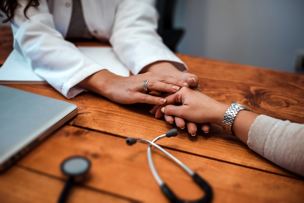 Foto mão de médico reconfortante seu paciente do sexo feminino. cuidados com o médico.