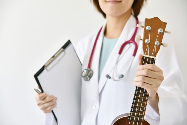 Mão de médico segurando o ukulele (instrumento musical), musicoterapia