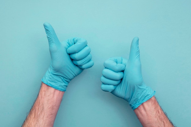 Mão de médicos usando luvas cirúrgicas protetoras dando sinal de polegar para cima