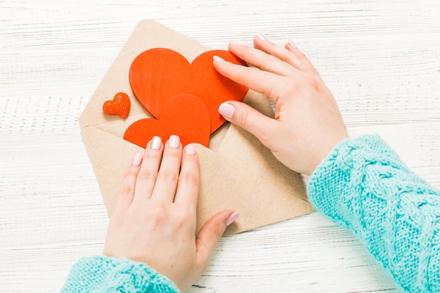 Mão de menina escrevendo carta de amor no dia de São Valentim Cartão postal artesanal com figura em forma de coração vermelho 14 de fevereiro celebração do feriado conceito de dia dos namorados com espaço de cópia