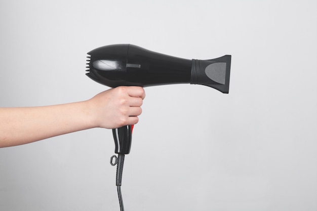 Mão de menina segurando o secador de cabelo.