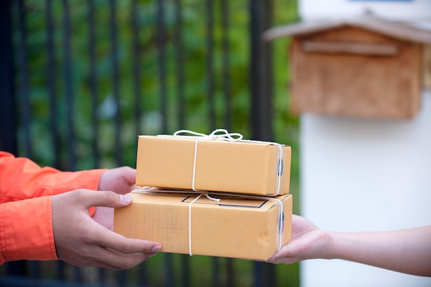 Mão de mulher aceitando uma entrega caixas marrons do conceito de entrega deliveryman