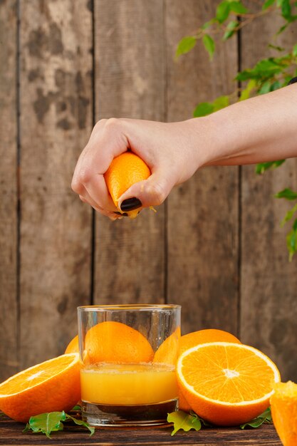 Foto mão de mulher aperta suco de laranja close-up